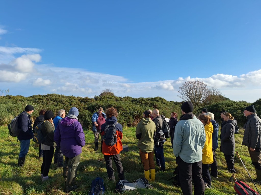 Group of people in a field listening to a trainer talking about small mammal recording.